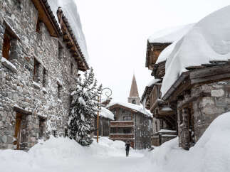 Explore the charm of this snow-covered village, featuring stone-built houses and a picturesque church steeple.