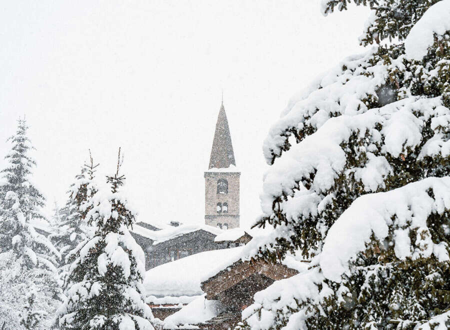 Nestled in a serene winter wonderland, this property offers stunning views of a snow-covered village and a charming church steeple.