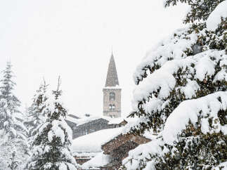 Nestled in a serene winter wonderland, this property offers stunning views of a snow-covered village and a charming church steeple.
