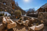 Experience luxury mountain living on this stunning stone patio, complete with plush seating and a rustic coffee table, perfect for enjoying breathtaking alpine views.