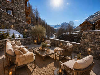 Experience luxury mountain living on this stunning stone patio, complete with plush seating and a rustic coffee table, perfect for enjoying breathtaking alpine views.