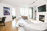 This stunning condo boasts a modern living space with a cozy fireplace and a sleek, mounted TV.