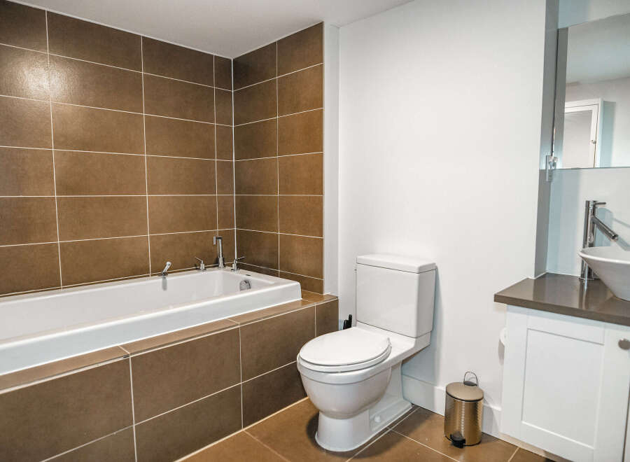 This modern bathroom features a sleek design with a built-in bathtub and stylish brown tile accents.