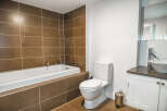 This modern bathroom features a sleek design with a built-in bathtub and stylish brown tile accents.