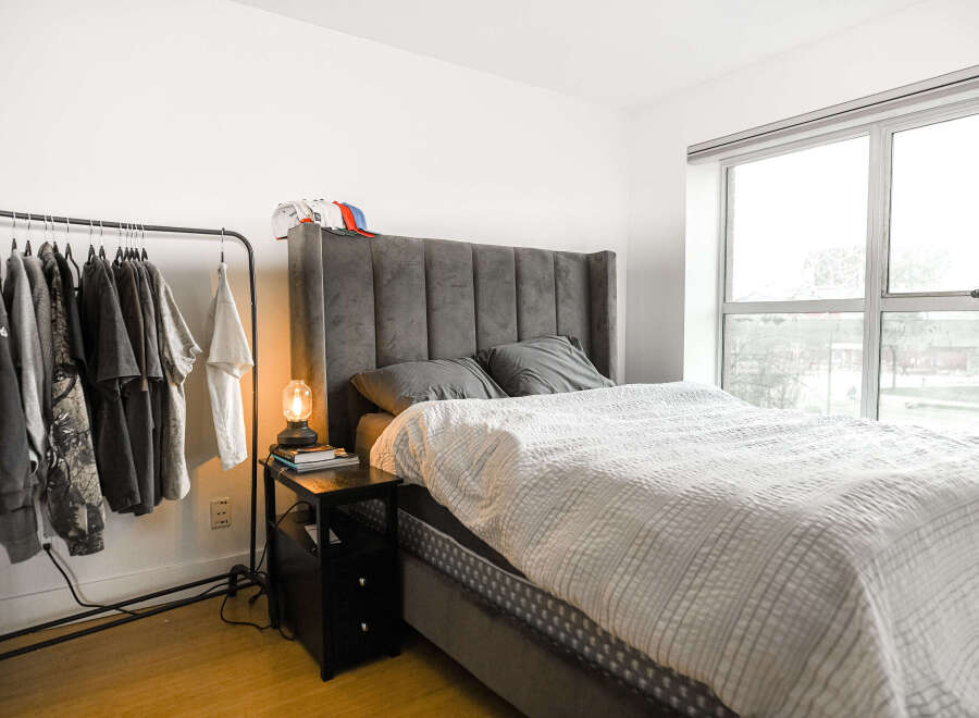 This modern bedroom features a stylish gray bed with a tufted headboard, offering a comfortable and elegant space.