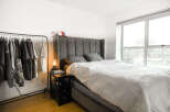 This modern bedroom features a stylish gray bed with a tufted headboard, offering a comfortable and elegant space.