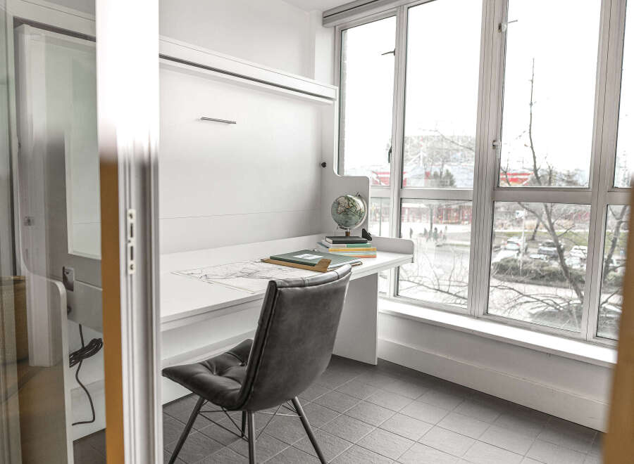 This modern home office features a sleek, minimalist design with a built-in desk and ample natural light.