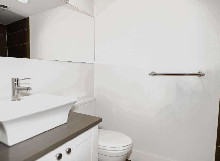 This modern bathroom features a sleek white sink and vanity, complemented by a stylish chrome faucet and towel rack.