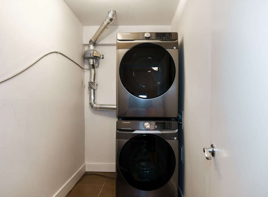 This modern laundry room features a sleek, stacked Samsung washer and dryer, maximizing space and efficiency.