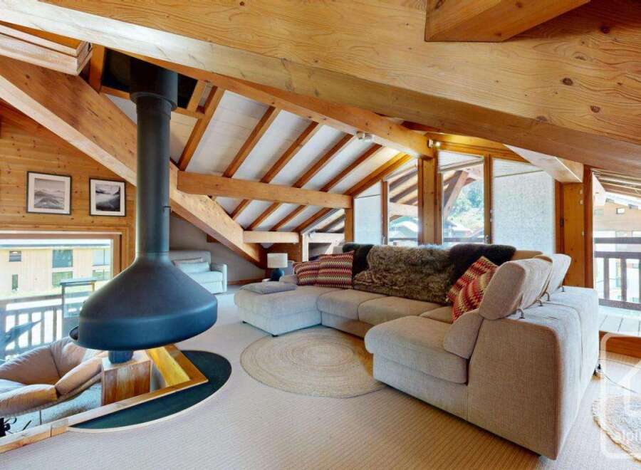Experience luxury living in this stunning chalet, featuring a cozy living area with a unique fireplace and exposed wooden beams.