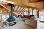Experience luxury living in this stunning chalet, featuring a cozy living area with a unique fireplace and exposed wooden beams.