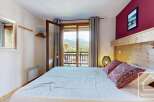 Experience the charm of this cozy bedroom, featuring a comfortable bed and a stunning mountain view from the balcony.