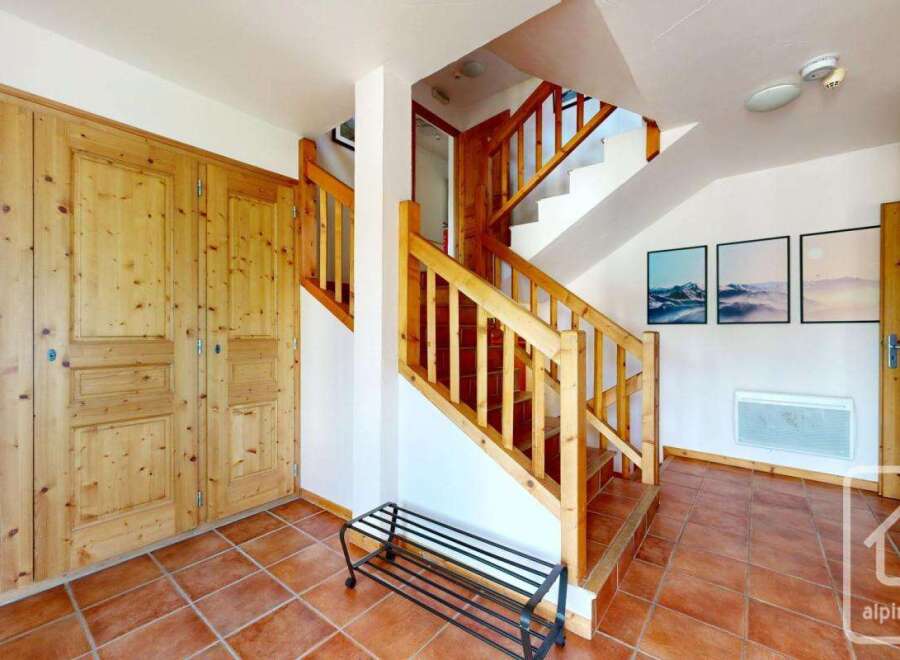 Step into this inviting entryway, featuring a stunning wooden staircase and warm, terracotta tile flooring.