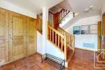 Step into this inviting entryway, featuring a stunning wooden staircase and warm, terracotta tile flooring.