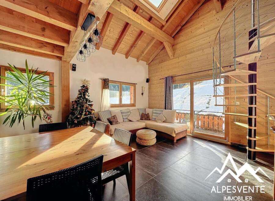 Discover the charm of this stunning chalet, featuring a cozy living area with a modern spiral staircase.