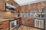 This stunning kitchen boasts beautiful wooden cabinetry and sleek stainless steel appliances, creating a warm and inviting atmosphere.
