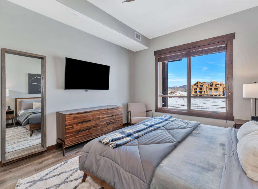 This stunning bedroom boasts a modern design with a touch of rustic charm, featuring a large window that offers breathtaking views of the surrounding landscape.