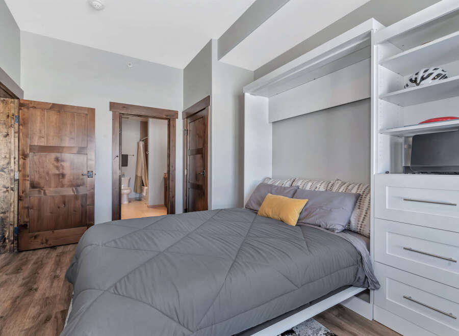 This cozy bedroom features a comfortable bed with a stylish gray comforter and decorative pillows.