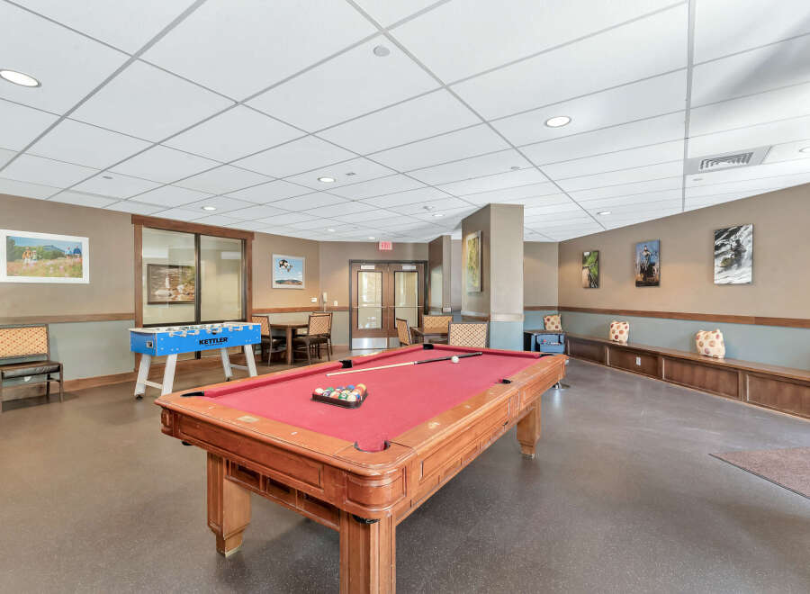 This inviting recreational space features a classic pool table with a vibrant red felt surface, perfect for friendly competition.