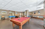 This inviting recreational space features a classic pool table with a vibrant red felt surface, perfect for friendly competition.