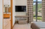 This stunning property boasts a modern bedroom design, featuring a sleek wall-mounted TV and a stylish wooden desk.