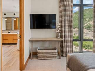 This stunning property boasts a modern bedroom design, featuring a sleek wall-mounted TV and a stylish wooden desk.