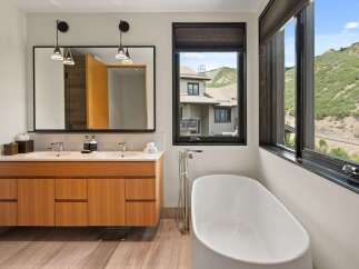 This luxurious bathroom boasts a modern design with a freestanding bathtub and a sleek double vanity.