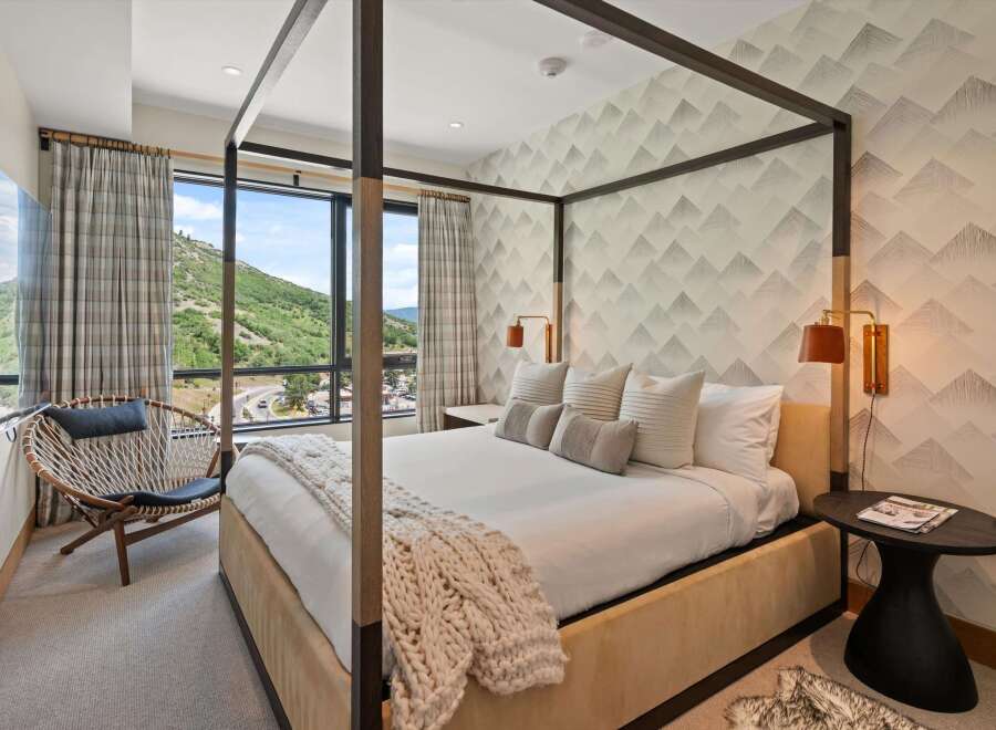 Experience luxury in this stunning bedroom featuring a modern four-poster bed and a cozy seating area.