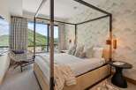 Experience luxury in this stunning bedroom featuring a modern four-poster bed and a cozy seating area.