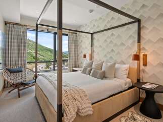 Experience luxury in this stunning bedroom featuring a modern four-poster bed and a cozy seating area.