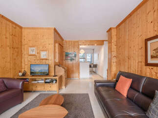 Step into this cozy living space, featuring warm wood paneling and a comfortable seating area.