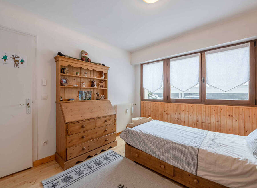 This charming bedroom features a cozy wooden bed frame and a stylish wooden dresser, perfect for a comfortable living space.