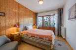 This cozy bedroom features a warm wooden wall and a comfortable bed with a colorful quilt.