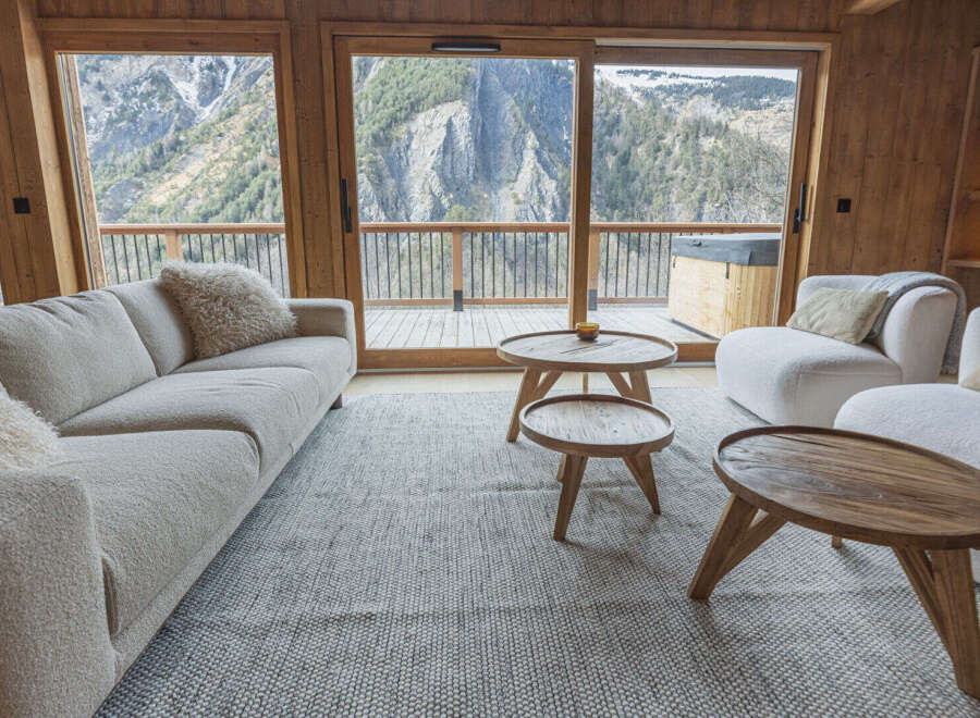 Experience breathtaking mountain views from this luxurious living room, featuring a plush sectional sofa and two cozy armchairs.