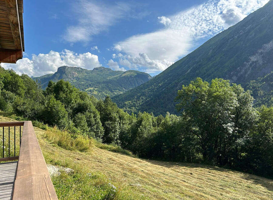 Experience breathtaking mountain views from this stunning property, featuring a spacious wooden deck perfect for enjoying the serene alpine landscape.
