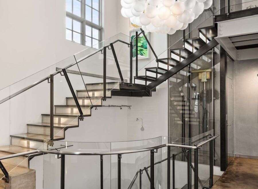 Step into luxury with this stunning property featuring a modern staircase design and an elegant chandelier.
