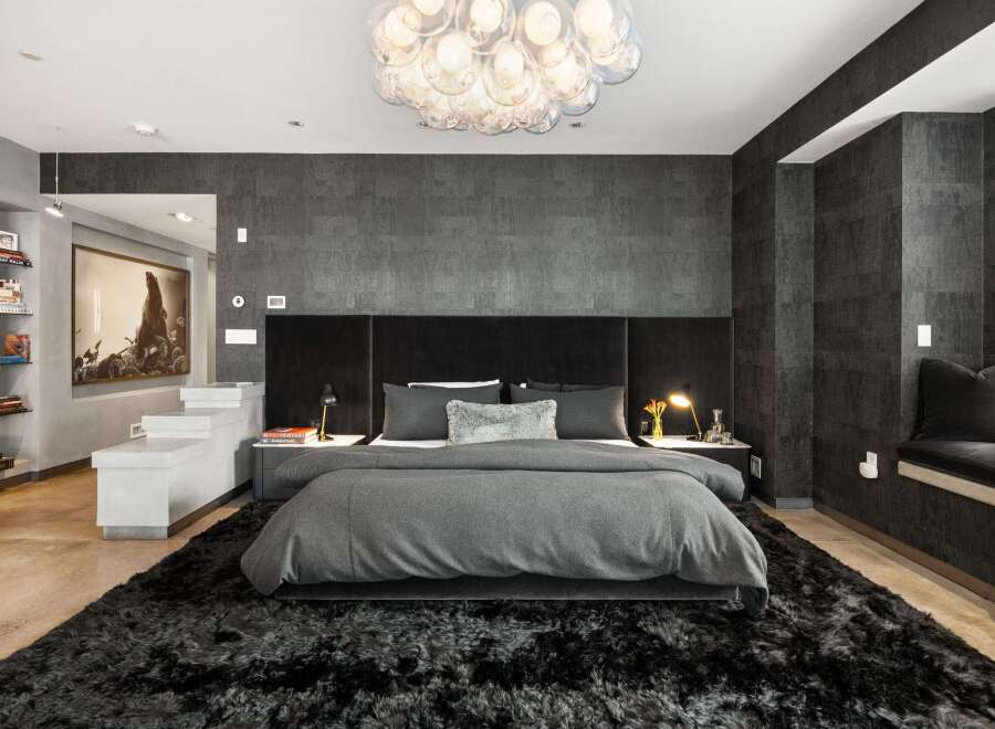 Experience luxury in this stunning bedroom featuring a plush, oversized rug and a statement chandelier.