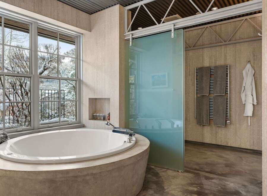 Indulge in the luxury of this spa-like bathroom, featuring a stunning oval soaking tub set within a concrete base.