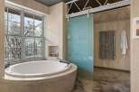 Indulge in the luxury of this spa-like bathroom, featuring a stunning oval soaking tub set within a concrete base.