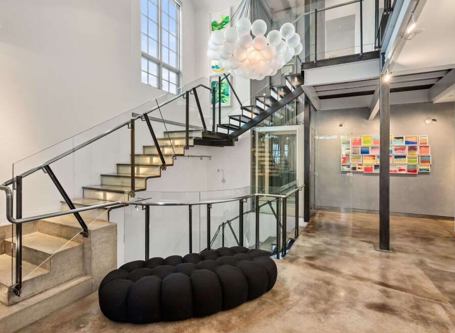 Step into luxury with this stunning property featuring a modern staircase with glass railings, a unique bubble-shaped sofa, and a captivating chandelier.