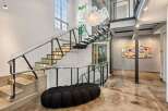 Step into luxury with this stunning property featuring a modern staircase with glass railings, a unique bubble-shaped sofa, and a captivating chandelier.