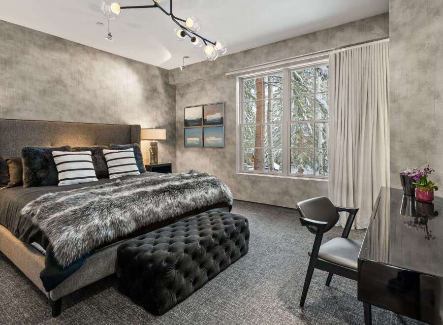 Experience luxury in this stunning bedroom featuring a plush bed with a faux fur throw and stylish accent pillows.