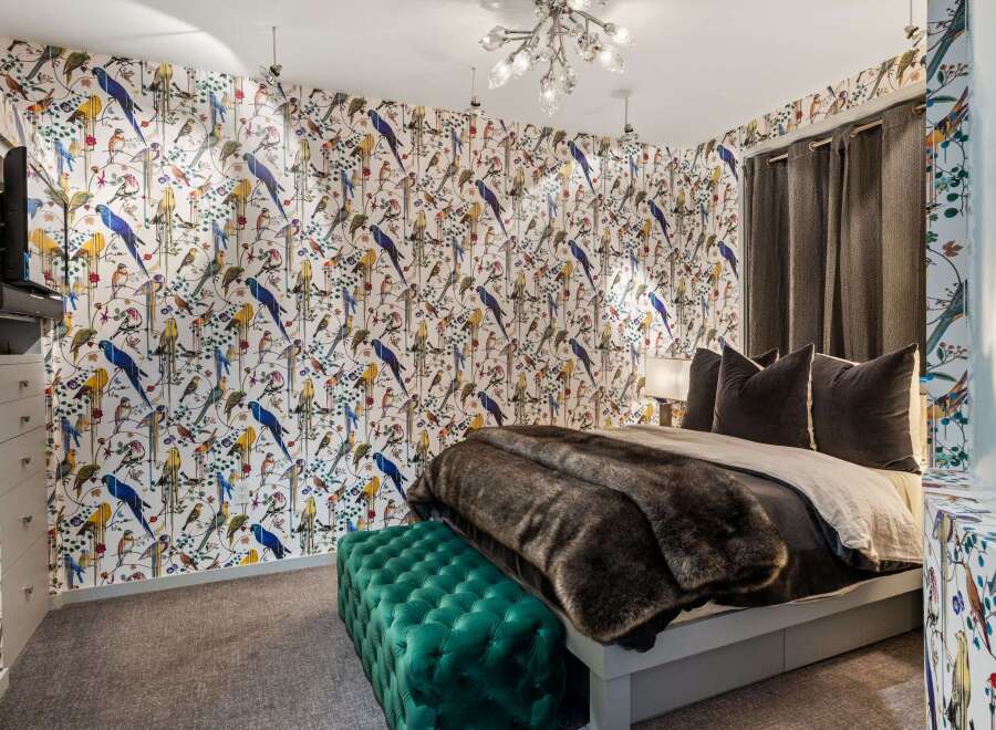 This stunning bedroom showcases a unique design with vibrant bird-patterned wallpaper, creating a focal point that adds character and charm.