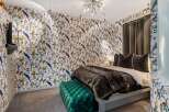 This stunning bedroom showcases a unique design with vibrant bird-patterned wallpaper, creating a focal point that adds character and charm.