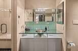 This modern bathroom showcases a sleek design with a glass countertop and a stylish vessel sink.