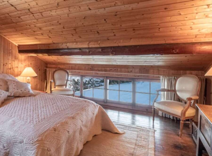 This cozy bedroom features a warm wooden interior and a stunning view of the snowy landscape outside.