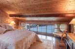 This cozy bedroom features a warm wooden interior and a stunning view of the snowy landscape outside.
