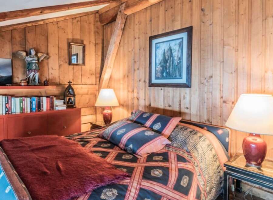 Step into a cozy bedroom retreat with rustic wood paneling and a touch of elegance.