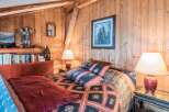 Step into a cozy bedroom retreat with rustic wood paneling and a touch of elegance.