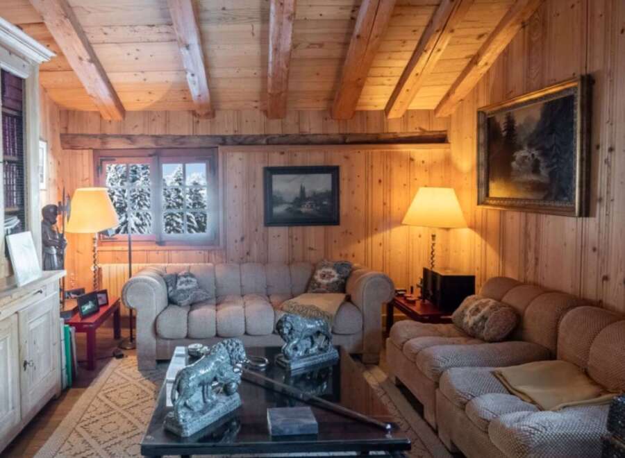 Step into a cozy retreat with this charming living space, featuring warm wooden paneling and exposed beams that create a rustic ambiance.